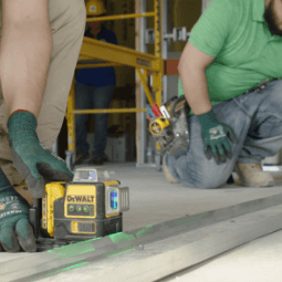 Two workers measure construction equipment