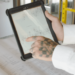 A construction worker looks at plans on a tablet